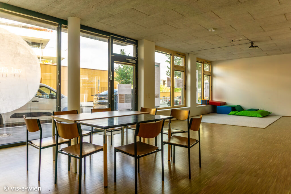 Innenansicht Grätzlraum mit Sesseln und Tischen vor Fenstern